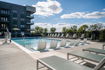 A pool area with sun loungers and a building in the background.
